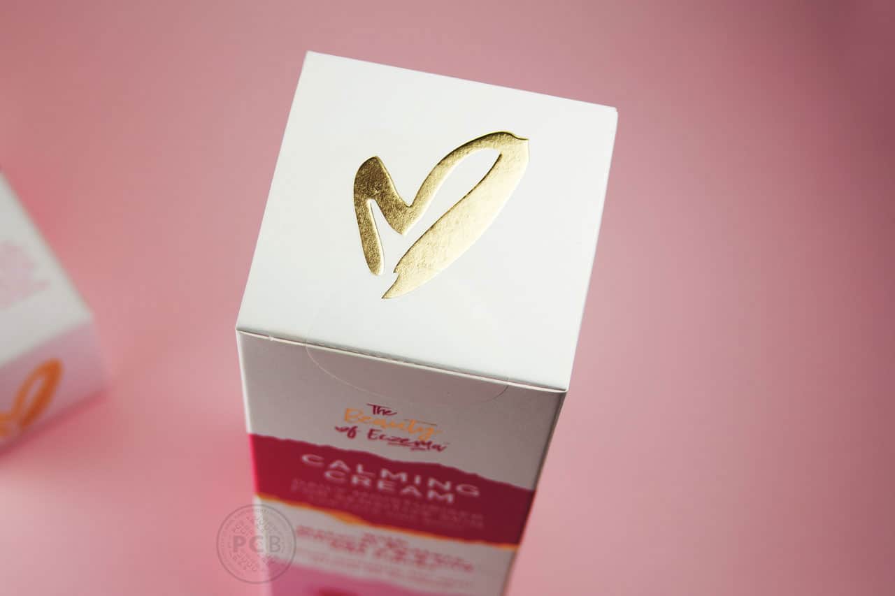 Embossed gold foil heart icon detail on top flap of skincare carton.